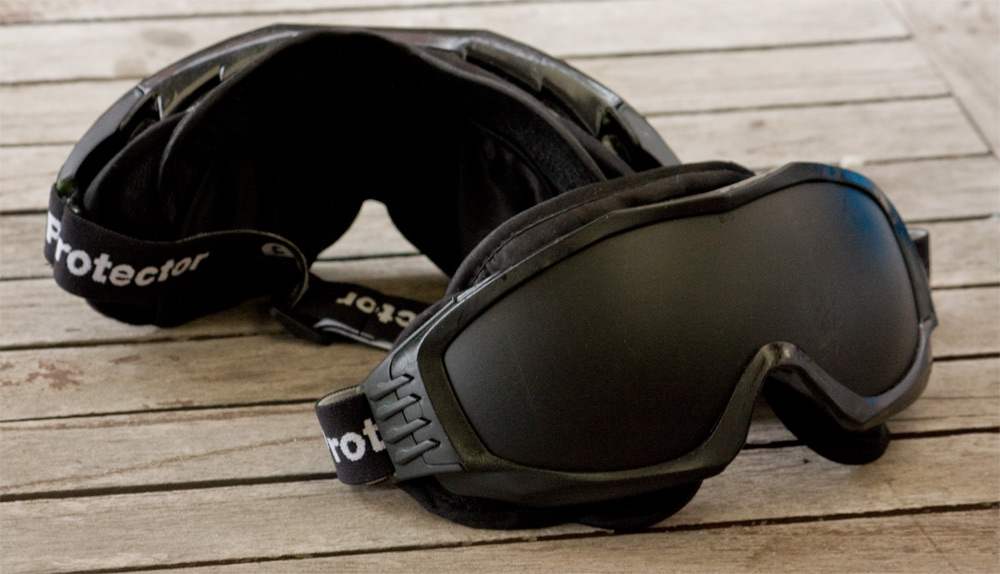 The front and back of a pair of goggles. The lenses are painted black and the insides are lined with plush fabric.